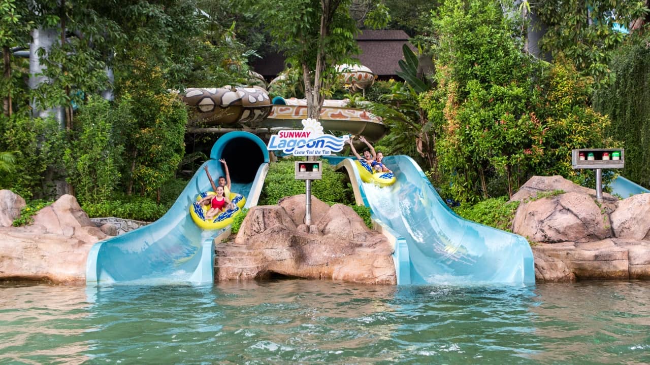Guests on yellow inner tubes sliding down water slides at Sunway Lagoon water park.
